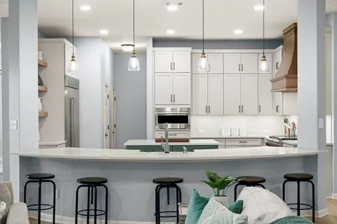a kitchen with kitchen island granite countertop a table chairs refrigerator and microwave