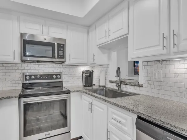 a kitchen with granite countertop white cabinets stainless steel appliances and a sink
