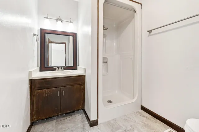 a bathroom with a sink a mirror a vanity and a shower