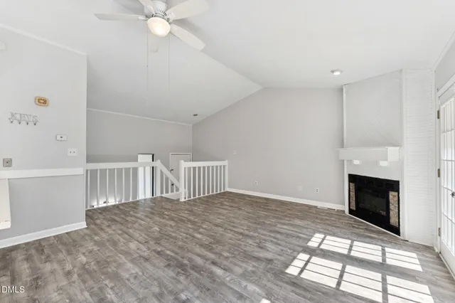a view of an empty room with chandelier fan and fire place