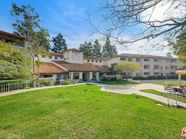 a view of a house with a big yard plants and large trees