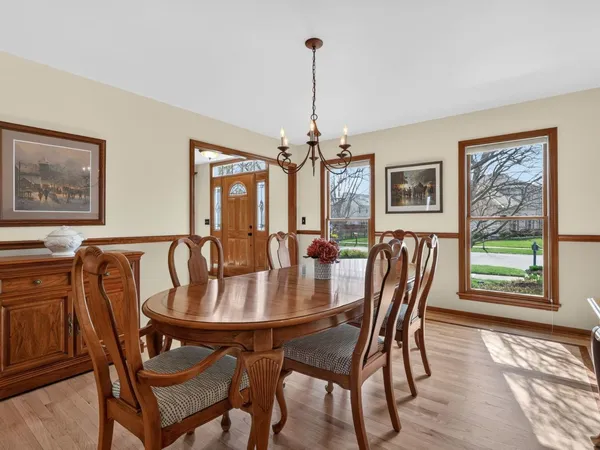 a kitchen with granite countertop a stove a sink a dining table and chairs with wooden floor