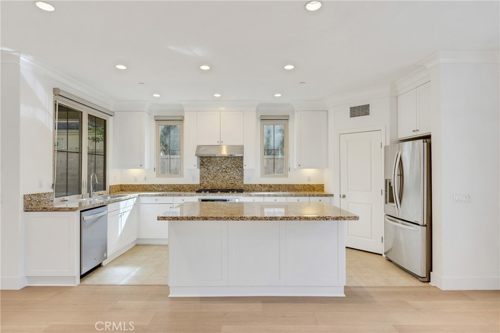 107 Hanging Garden Irvine, CA 92620 - Photo 5 of 26 a kitchen with stainless steel appliances granite countertop a stove top oven a refrigerator a sink and white cabinets
