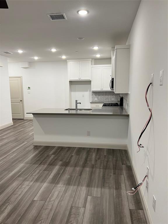 6041 Roper Road McKinney, TX 75070 - Photo 6 of 24 Modern kitchen featuring white cabinetry, a gray solid surface countertop island with integrated sink, and a contrasting tile backsplash