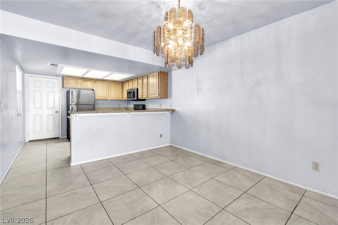 6250 West Flamingo Road, Unit 98 Las Vegas, NV 89103 - Photo 5 of 40 Kitchen featuring a peninsula, a notable chandelier, stainless steel appliances, hanging light fixtures, and light tile patterned floors