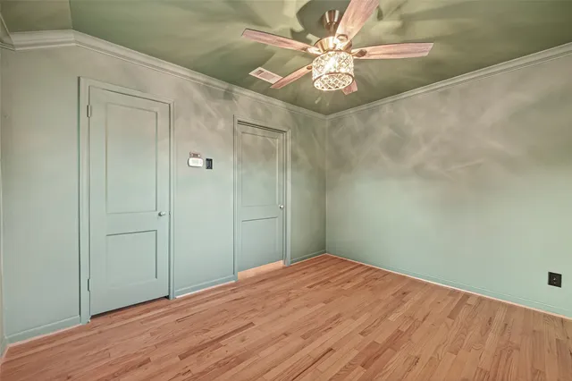 a view of a big room with wooden floor and a chandelier fan
