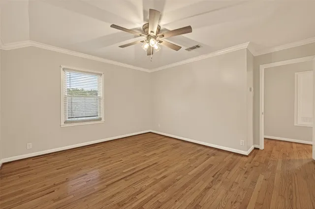 an empty room with wooden floor chandelier fan and windows