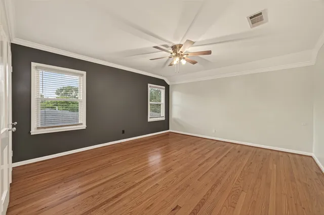 a view of empty room with wooden floor and fan
