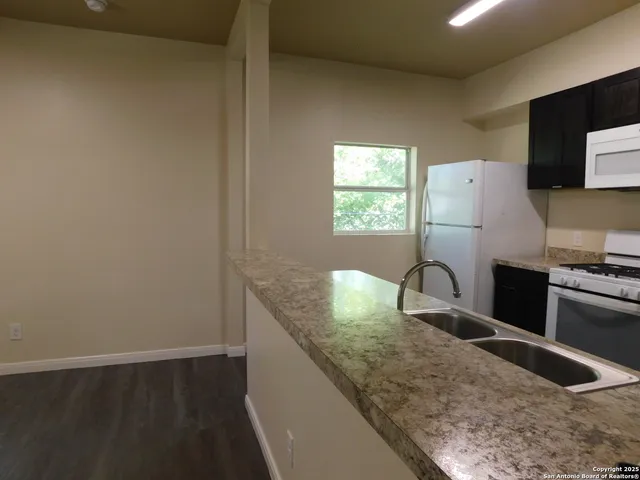 a view of kitchen island with stainless steel appliances granite countertop a sink and a stove top oven