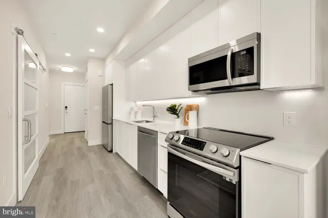 a kitchen with stainless steel appliances a stove microwave and refrigerator