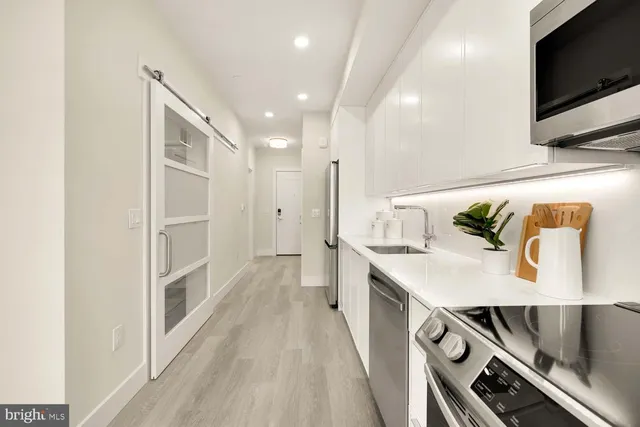 a kitchen with kitchen island white cabinets and stainless steel appliances