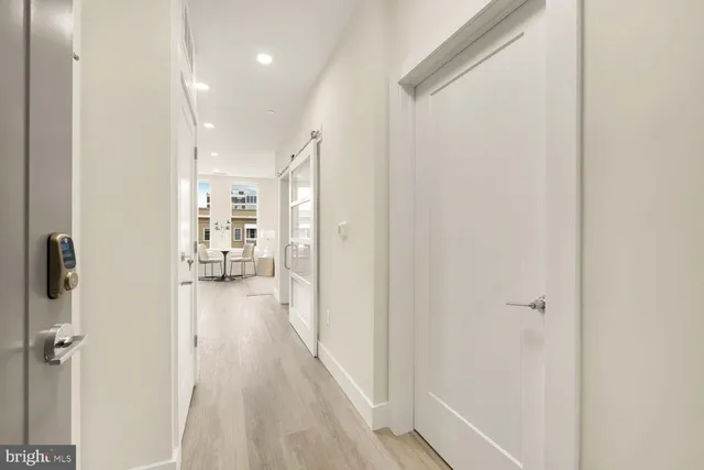 a view of a hallway with wooden floor and a bathroom