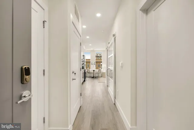 a view of a hallway with wooden floor and a bathroom
