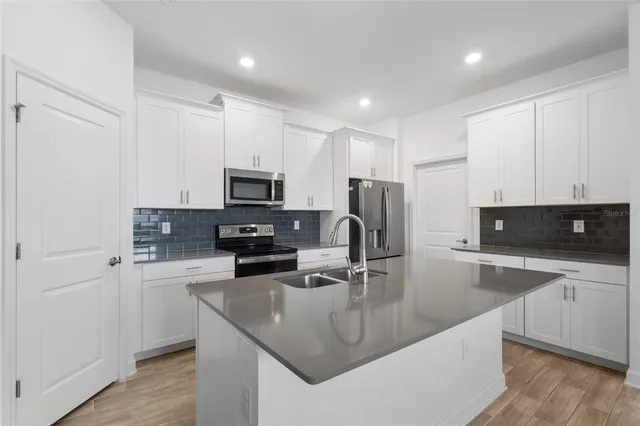 a kitchen with stainless steel appliances granite countertop a sink a stove and a refrigerator