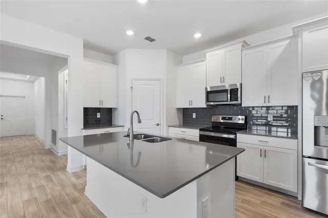 a kitchen with kitchen island a sink stove microwave and refrigerator