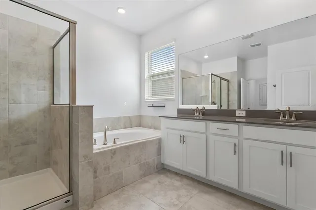 a bathroom with a double vanity sink large mirror and bathtub