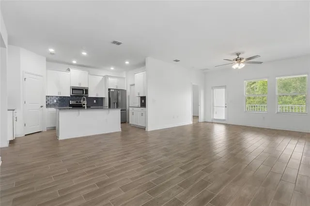 a view of a big room with wooden floor and a kitchen