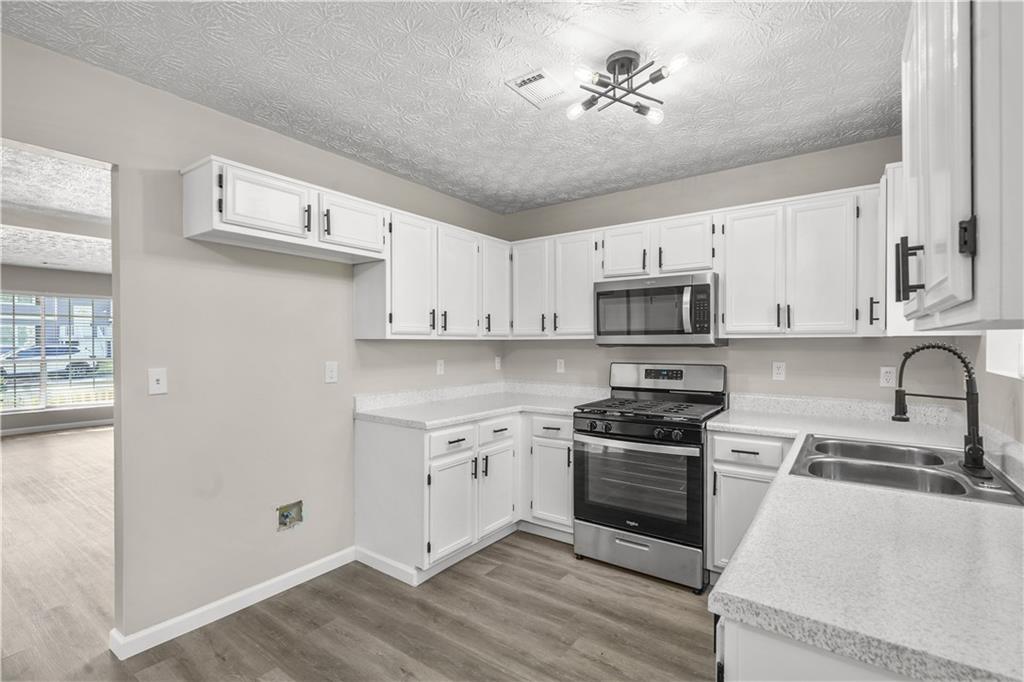 826 Shore Drive Lithonia, GA 30058 - Photo 11 of 42 a kitchen with stainless steel appliances a stove a sink and a refrigerator