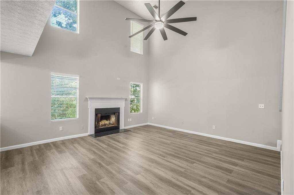 826 Shore Drive Lithonia, GA 30058 - Photo 3 of 42 an empty room with windows a fireplace a ceiling fan and wooden floor
