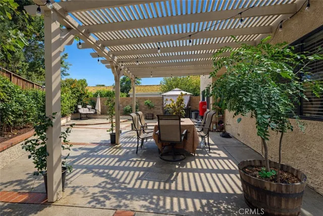 a view of a patio with table and chairs potted plants and large tree
