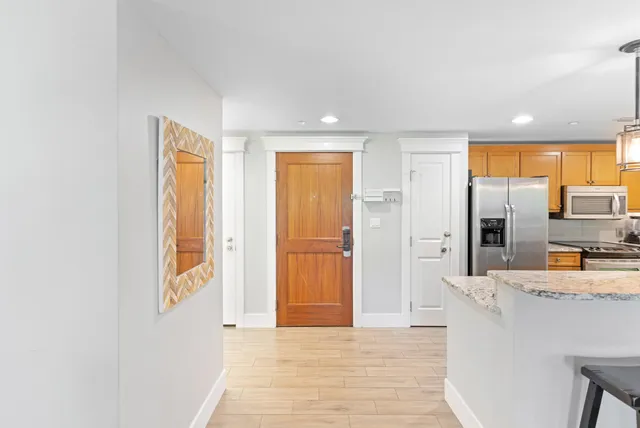 a view of a kitchen with kitchen island granite countertop wooden floor and refrigerator