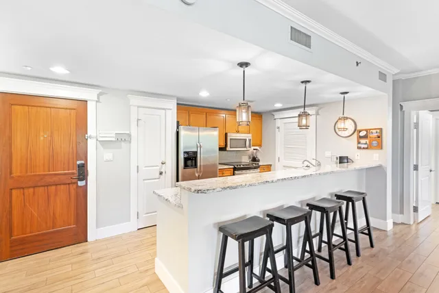 a kitchen with a table chairs refrigerator and wooden floor