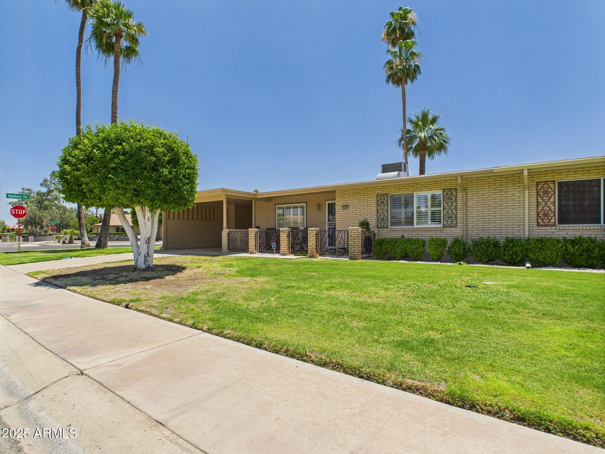9915 West Mountain View Road Sun City, AZ 85351 - Photo 2 of 22 a front view of a house with a yard and palm trees