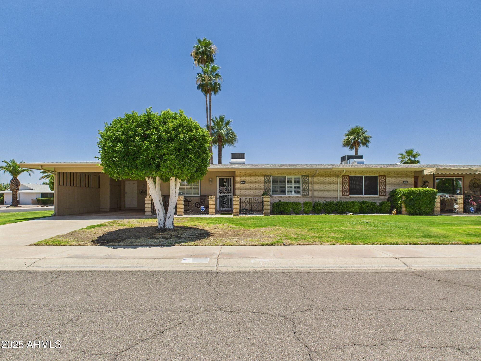 9915 West Mountain View Road Sun City, AZ 85351 - Photo 3 of 22 a front view of a house with a yard and potted plants