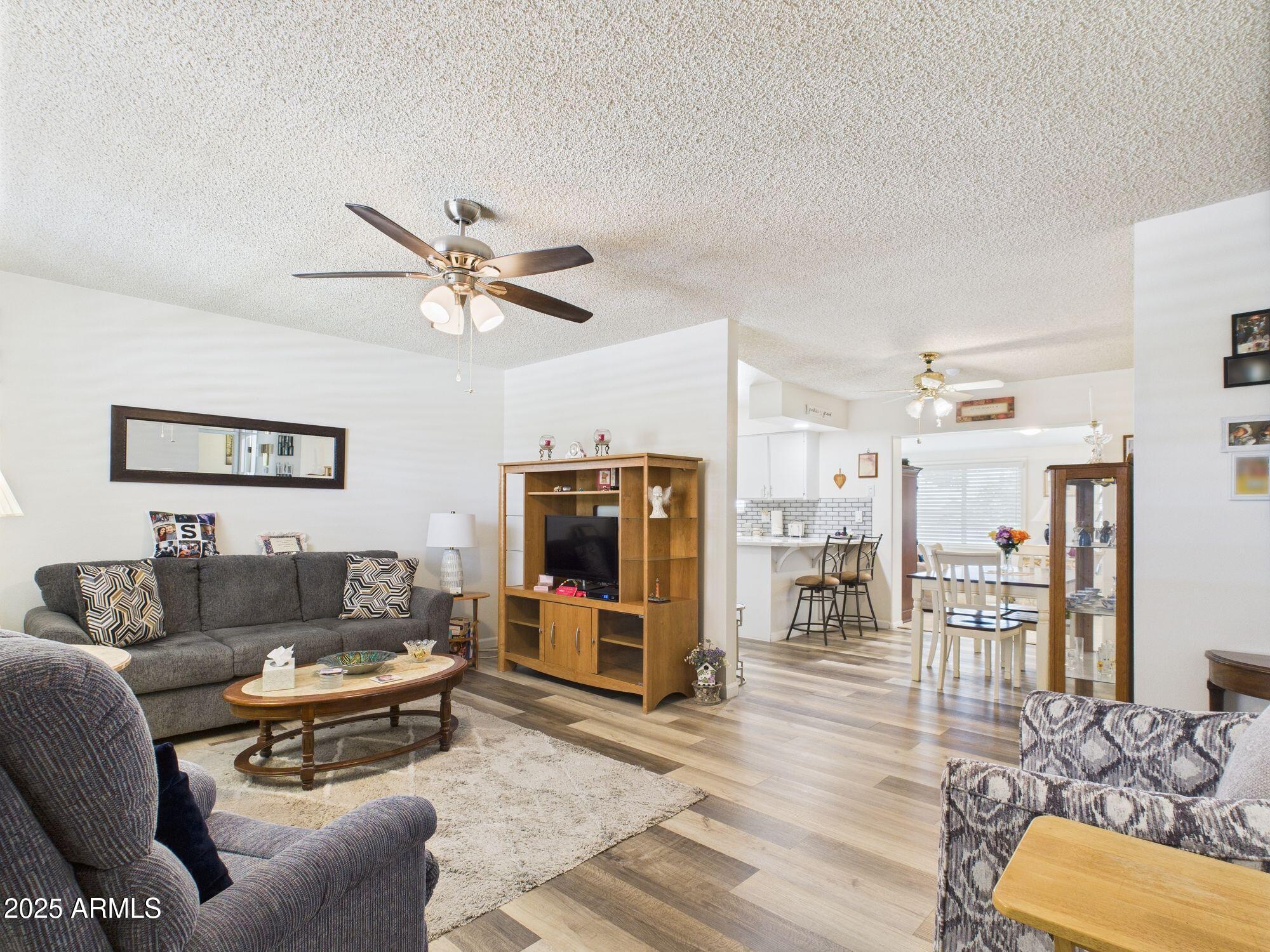 9915 West Mountain View Road Sun City, AZ 85351 - Photo 5 of 22 a living room with furniture kitchen view and a flat screen tv