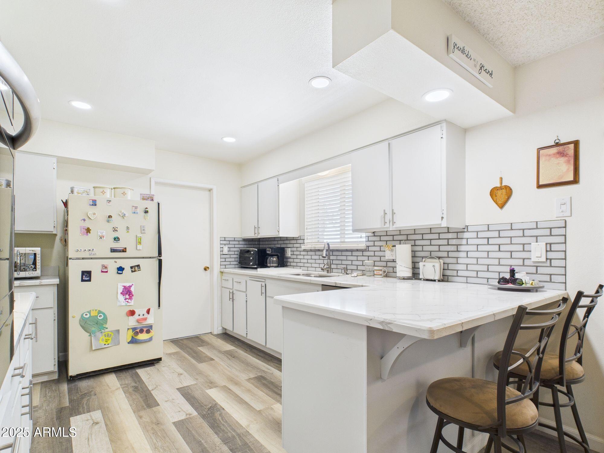 9915 West Mountain View Road Sun City, AZ 85351 - Photo 9 of 22 a kitchen with a sink a stove a refrigerator and cabinets