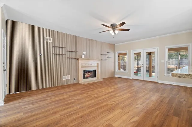 a view of an empty room with wooden floor and a kitchen