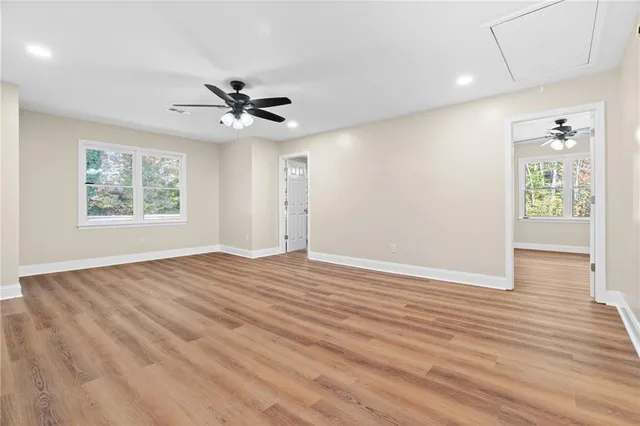 a view of an empty room with a window and wooden floor