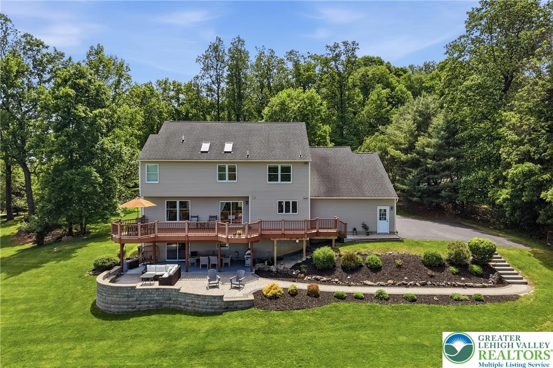 115 West Butternut Road Hellertown, PA 18055 - Photo 67 of 97 A spacious elevated deck and ground-level patio provide ample outdoor living against a backdrop of mature trees.