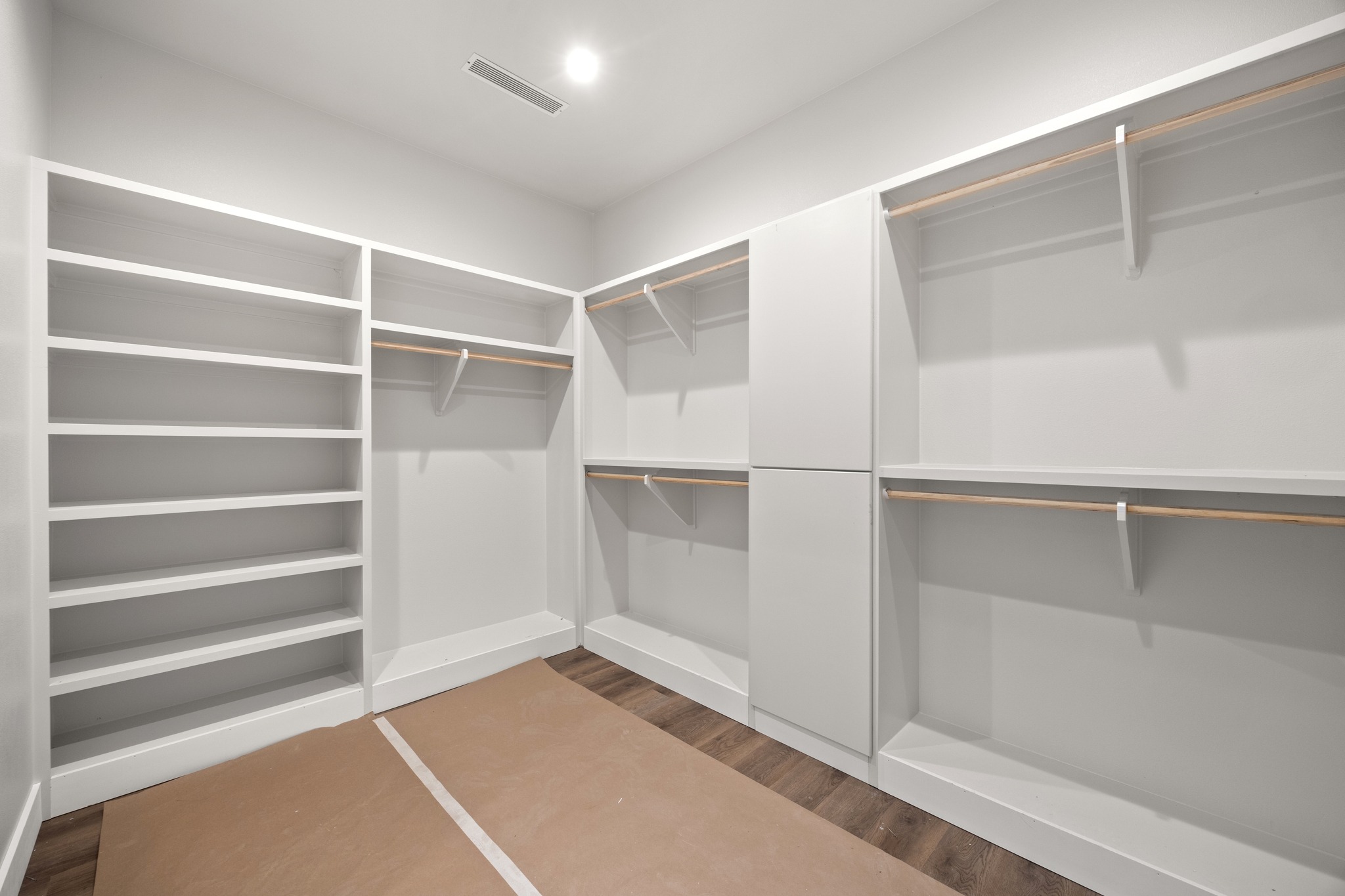 903 Flint Ridge Trail Georgetown, TX 78628 - Photo 24 of 39 Spacious walk-in closet featuring extensive built-in shelving, multiple hanging rods, closed cabinetry, wood-finish flooring, and recessed lighting