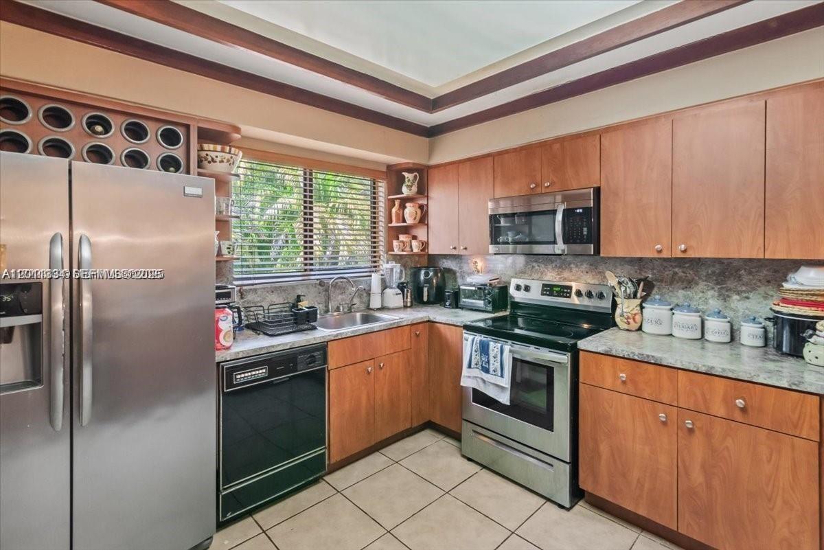 6385 Southwest 25th Street Miami, FL 33155 - Photo 7 of 28 a kitchen with stainless steel appliances granite countertop a stove a sink dishwasher a refrigerator and a microwave