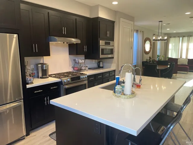 a kitchen with kitchen island a sink a stove a refrigerator and chairs