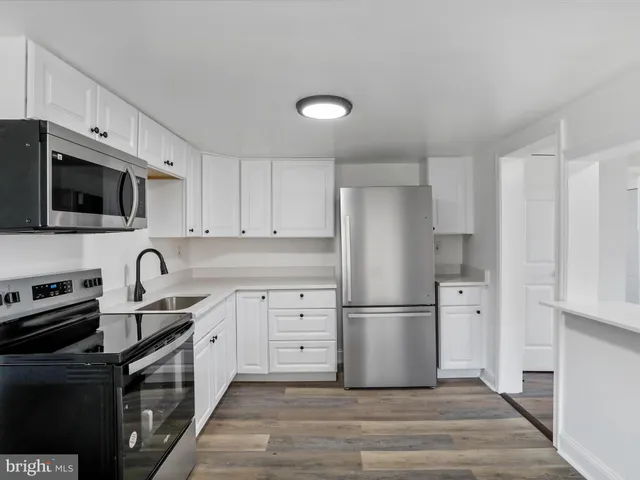 a kitchen with granite countertop a refrigerator stove and sink