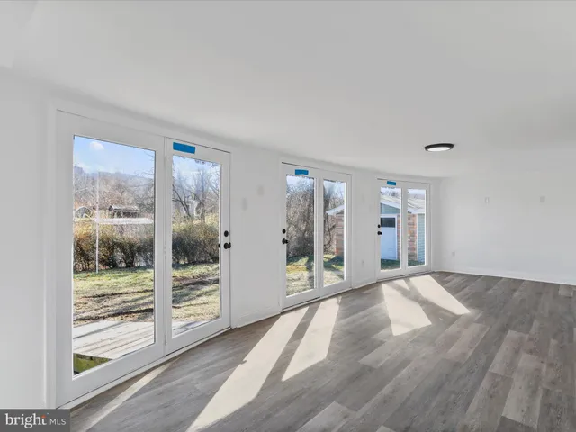 a view of empty room with wooden floor and floor to ceiling window