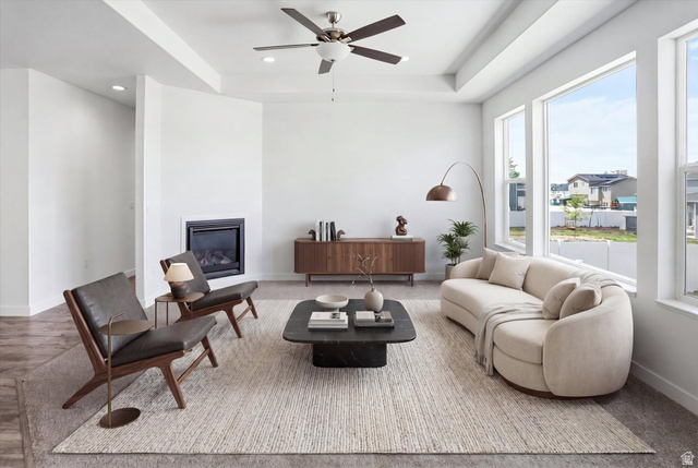 3636 West 910 South Syracuse, UT 84075 - Photo 38 of 70 Spacious living area featuring a corner-mounted fireplace, multiple large windows, tray ceilings, recessed lighting, and a ceiling fan
