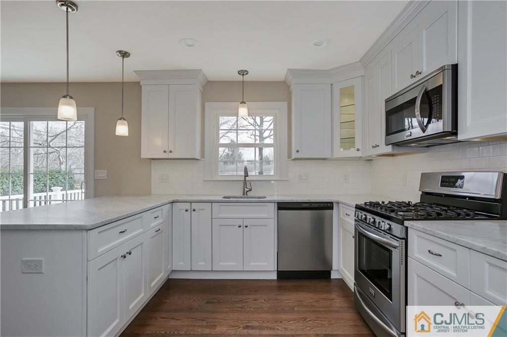1103 Sawmill Road Mountainside, NJ 07092 - Photo 7 of 25 a kitchen with stainless steel appliances white cabinets granite counter tops and a wooden floors
