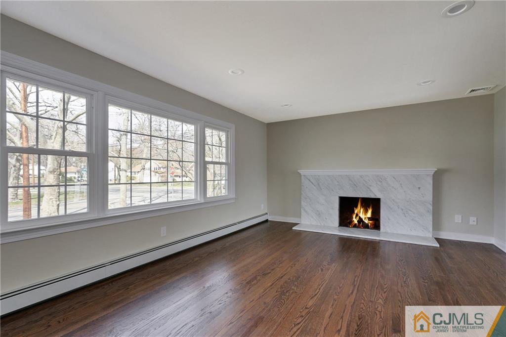 1103 Sawmill Road Mountainside, NJ 07092 - Photo 9 of 25 an empty room with wooden floor fire place and windows