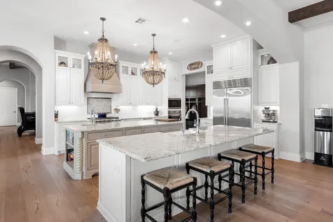 a kitchen with stainless steel appliances granite countertop a white cabinets and chandelier