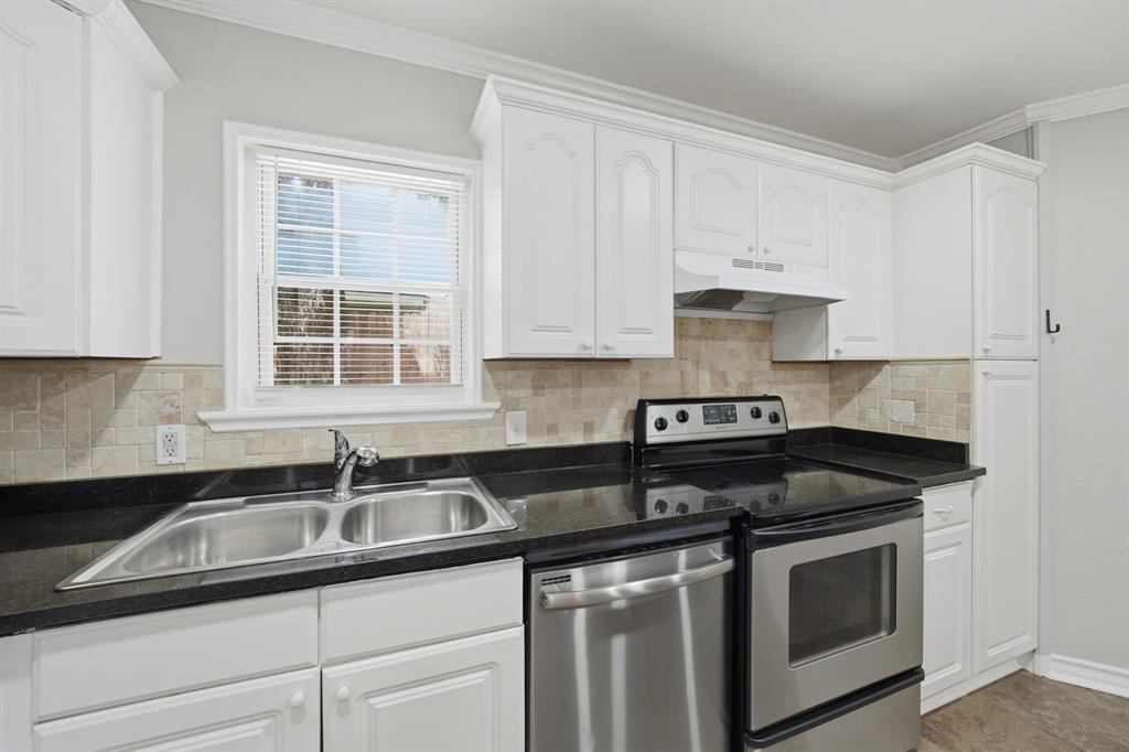 1108 Billie Ruth Lane Hurst, TX 76053 - Photo 12 of 27 Kitchen featuring white cabinetry, black countertops, stainless steel appliances, a double basin sink, and a tiled backsplash
