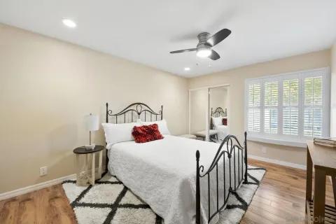 a bedroom with a bed a dresser and windows