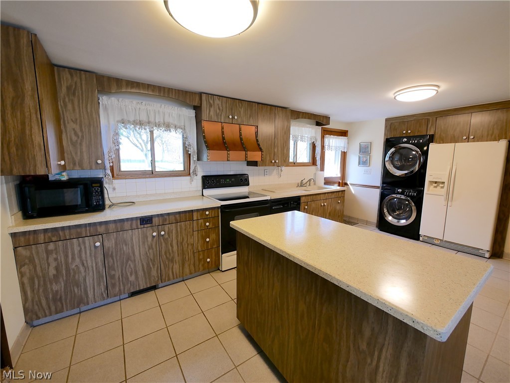 57500 Hospital Road Bellaire, OH 43906 - Photo 20 of 22 Kitchen with stacked washer / dryer, white appliances, sink, light tile floors, and premium range hood