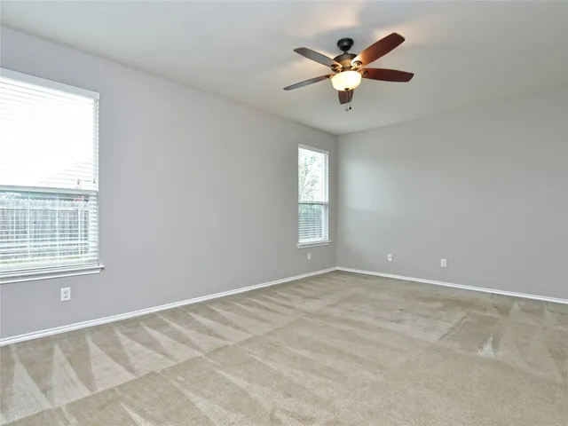 an empty room with window and ceiling fan