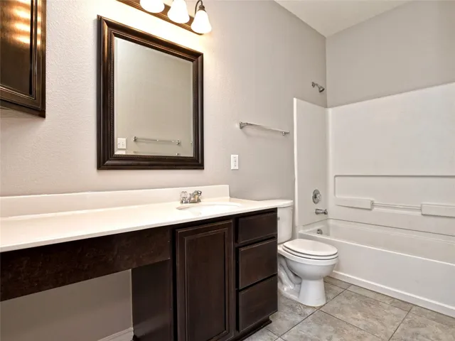 a bathroom with a toilet sink vanity tub and mirror
