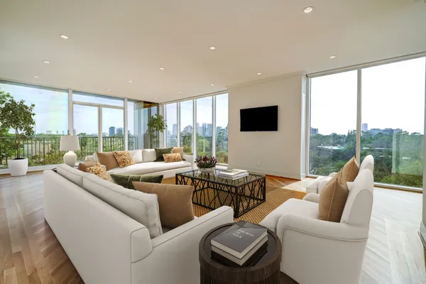 a living room with furniture floor to ceiling window and a flat screen tv