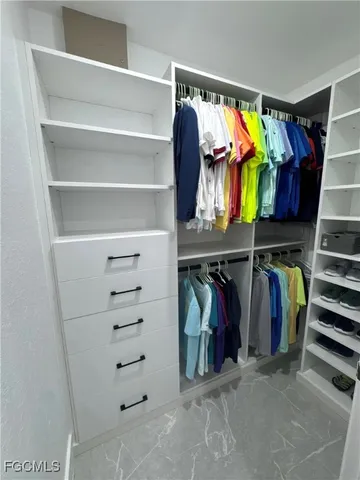 a view of walk in closet with clothes and shoes