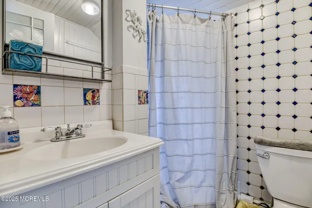 a bathroom with a sink a toilet and shower curtain